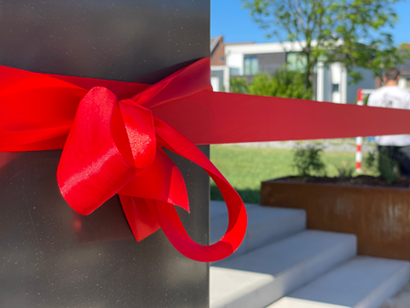 ruban rouge lié en noeud sur un poteau d'un batiment qui est inaugurer