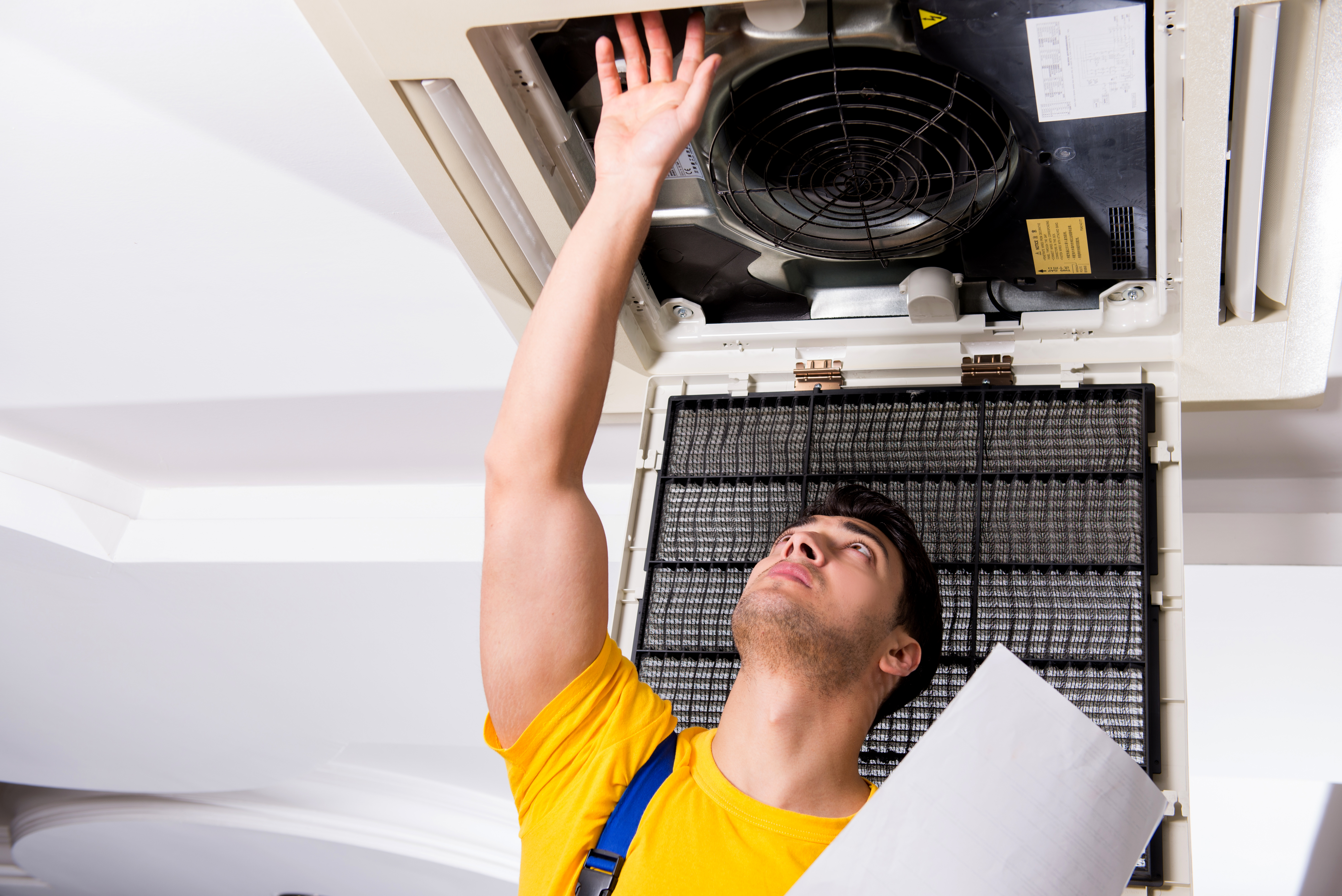 Repairman repairing ceiling air conditioning unit