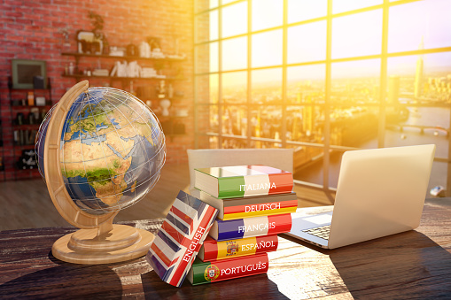 Books with covers in colors of flags of Europe countries, laptop and globe on a table in a modern interiorSource page for the map texture: http://visibleearth.nasa.gov/view.php?id=57730